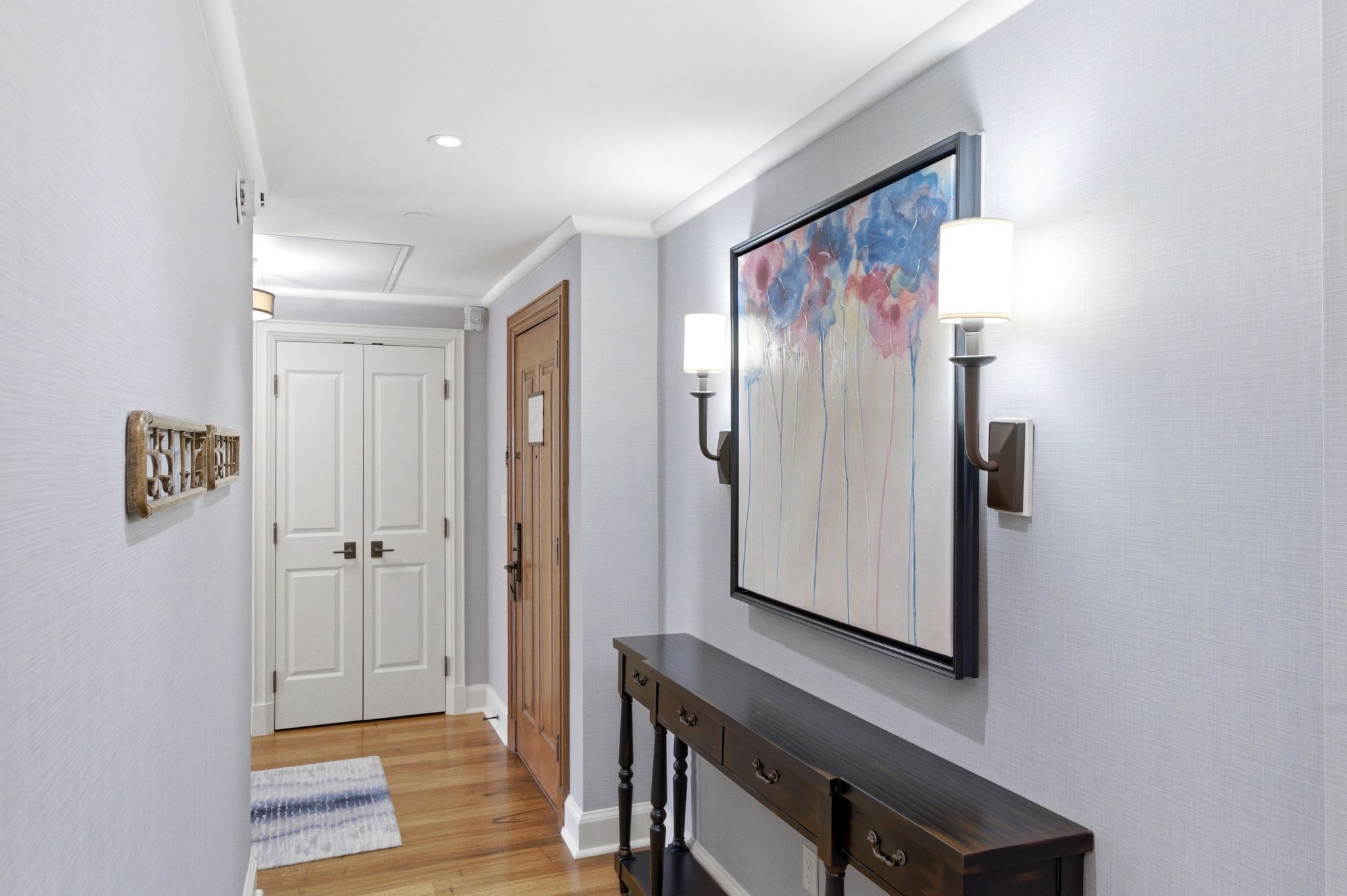 Hallway featuring wood-finish flooring, light blue textured wallpaper, and recessed ceiling lighting