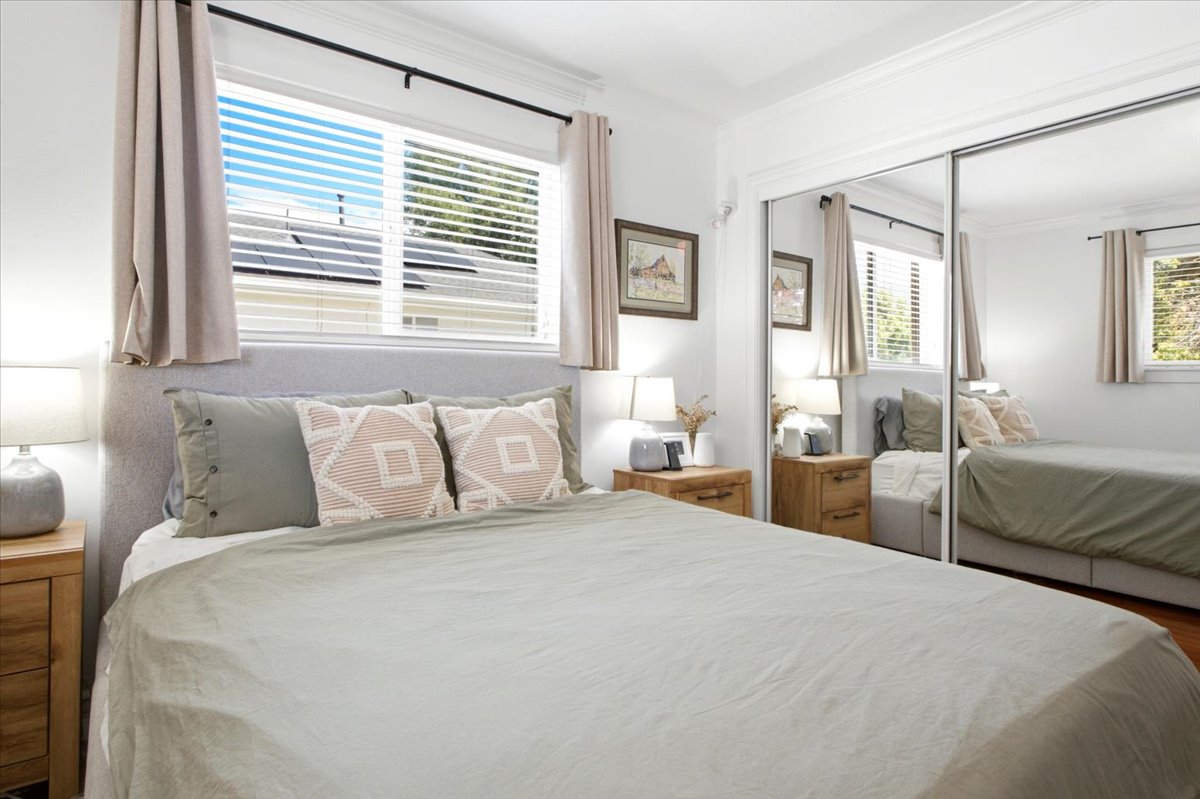 Bedroom featuring an upholstered headboard, dual bedside tables, and a full-wall mirrored closet