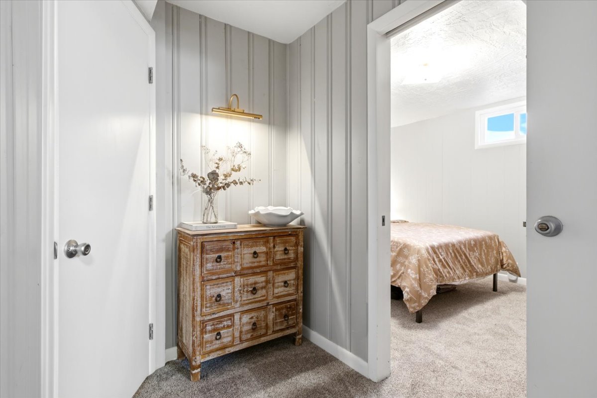 Hallway featuring vertical paneling, a wall-mounted light fixture, and carpet flooring