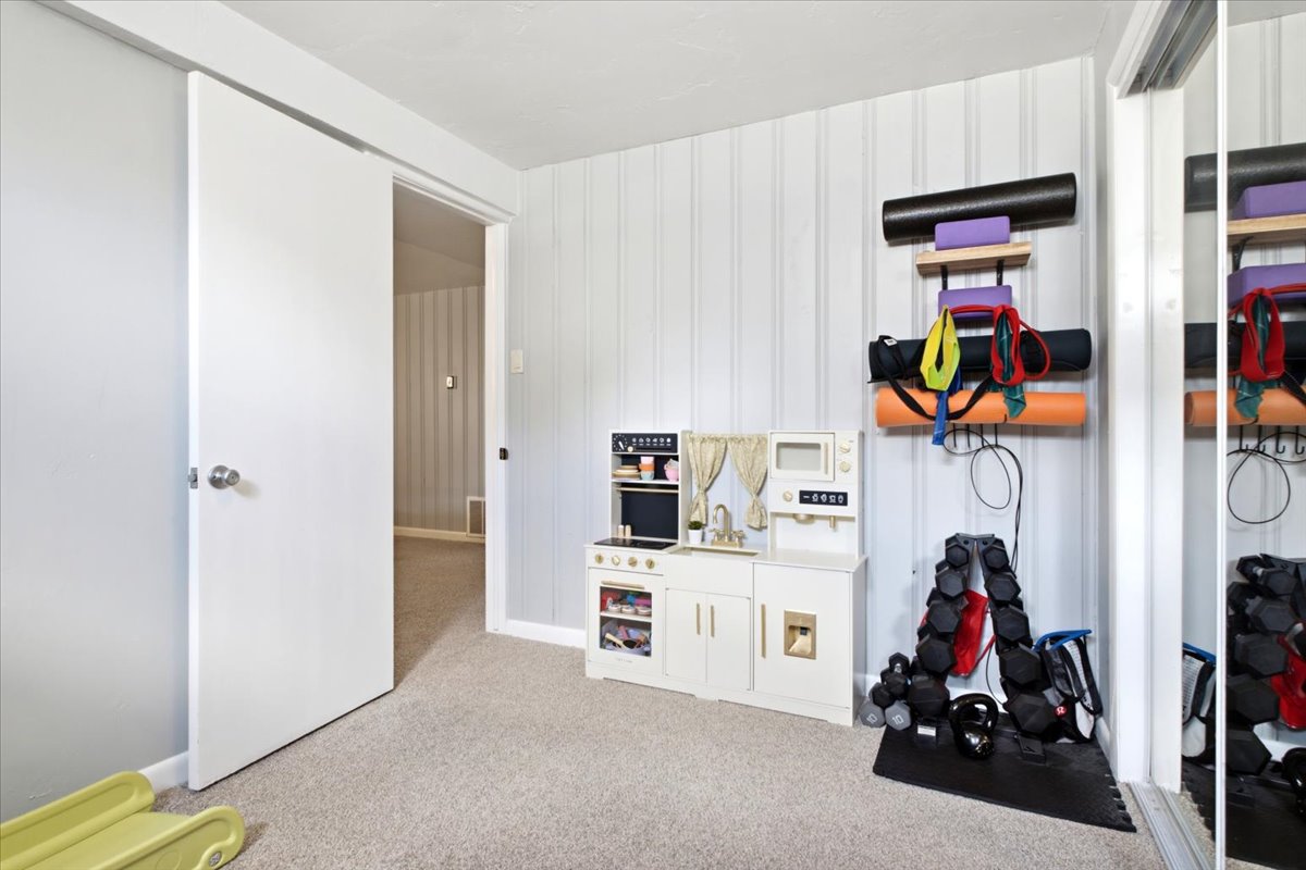 Carpeted room featuring a white paneled accent wall, light gray painted walls, and a white sliding barn door entry