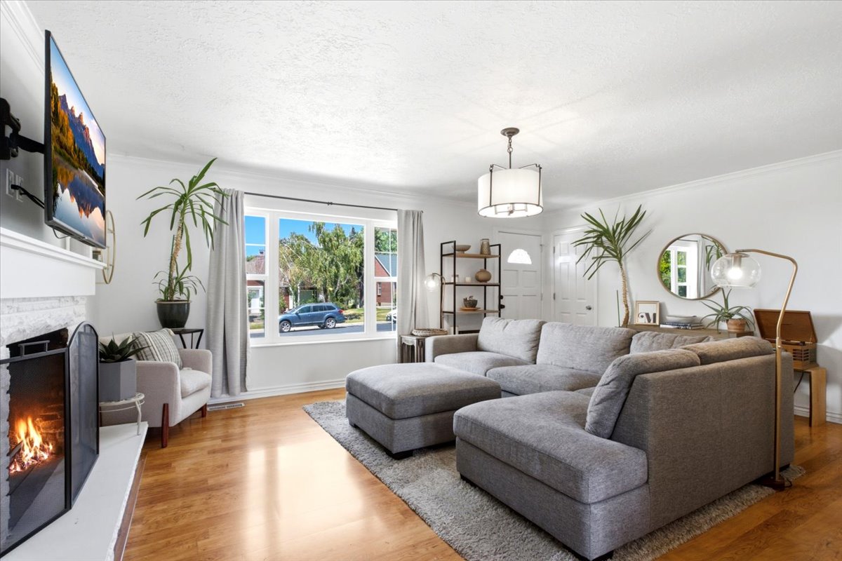 Luminous living space featuring wood-finish flooring, a white brick fireplace with a mantel, and a multi-pane window