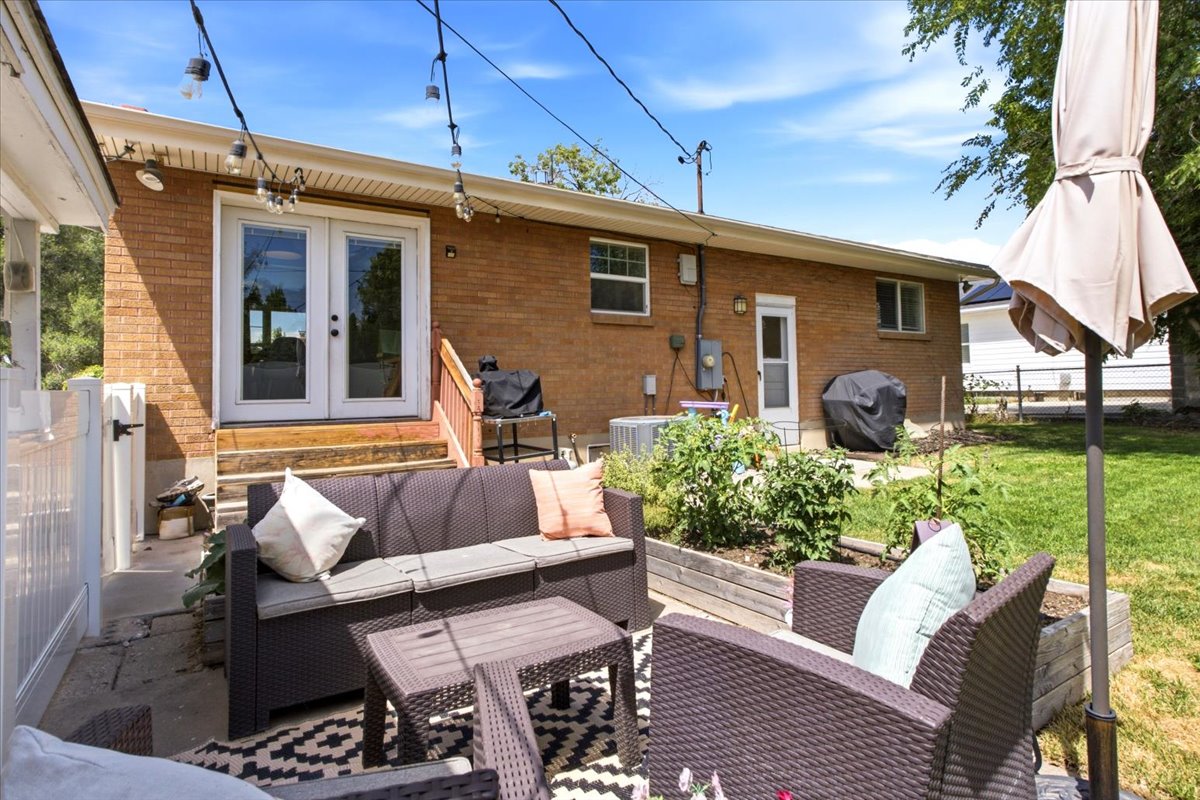 Patio area featuring concrete flooring, a white privacy fence, and string lighting