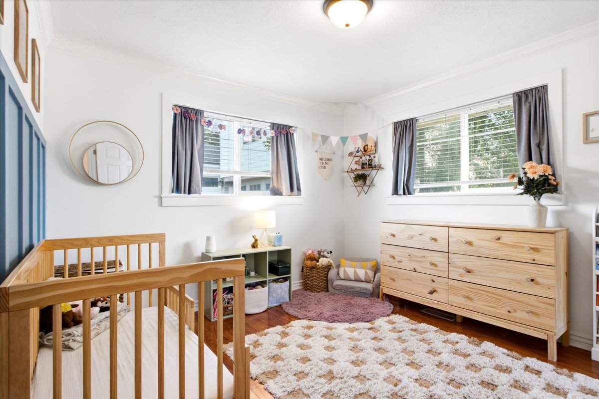 Bright room featuring two windows, crown molding, wood-finish flooring, and a ceiling-mounted light fixture