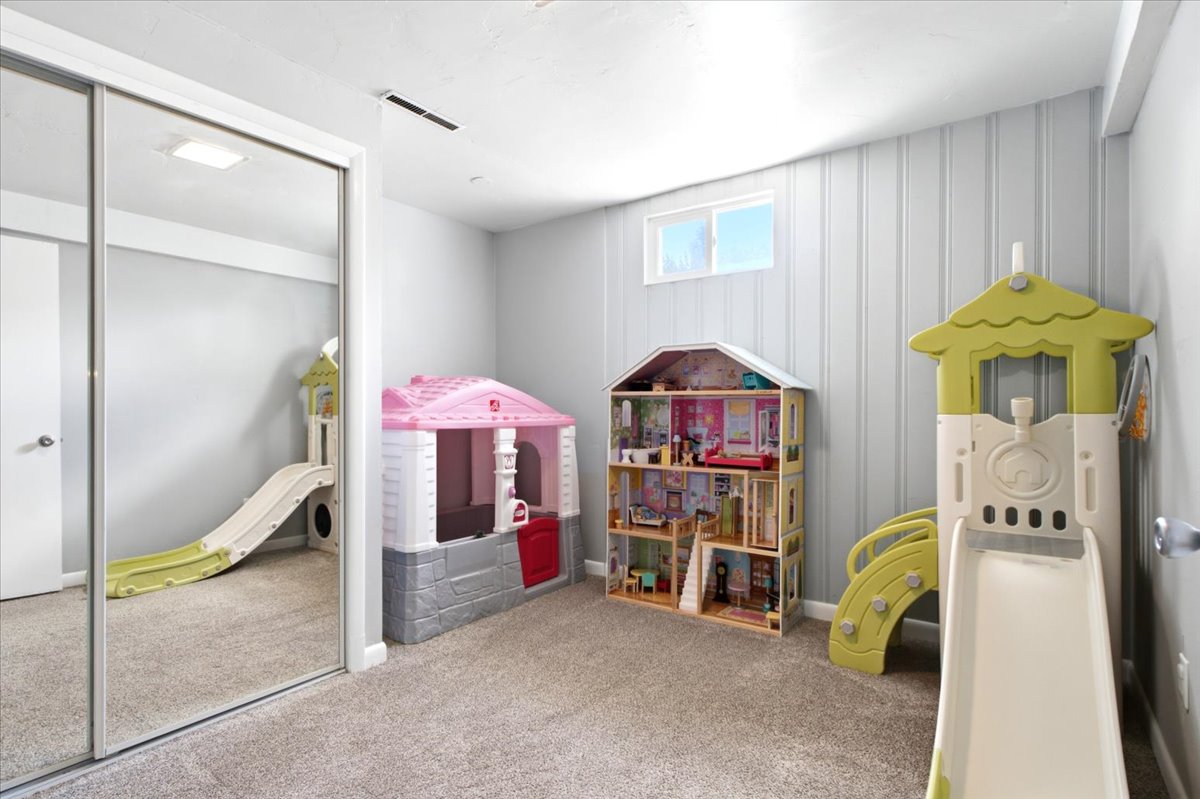 Carpeted room featuring a mirrored closet, a horizontal window, and a wall with vertical paneling