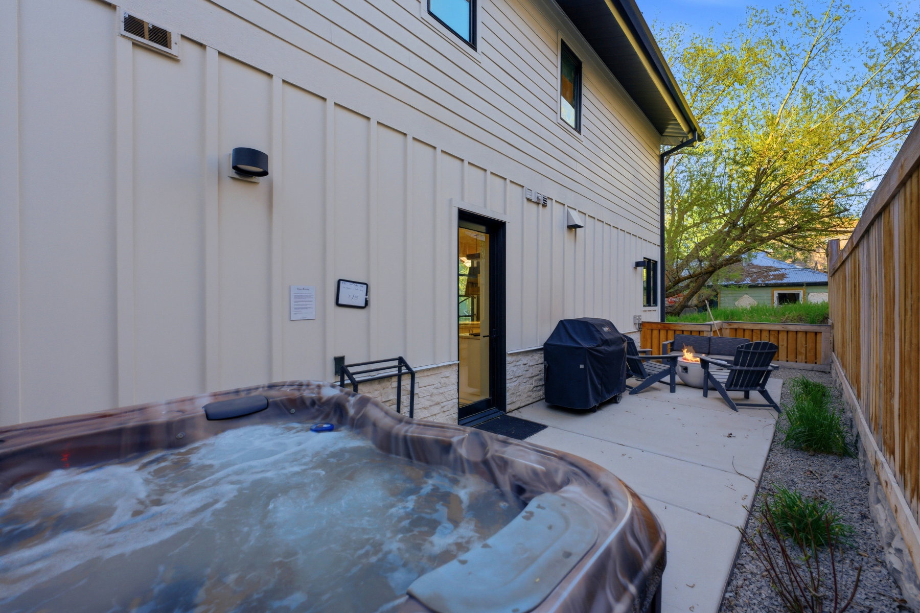 Outdoor patio featuring a hot tub, concrete paving, and a wooden privacy fence