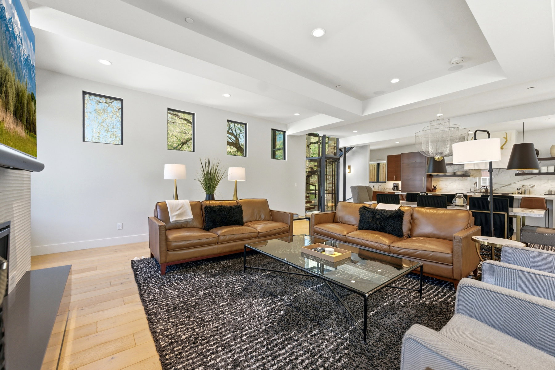 Open-concept living area featuring light wood-finish flooring, recessed lighting, and a tray ceiling
