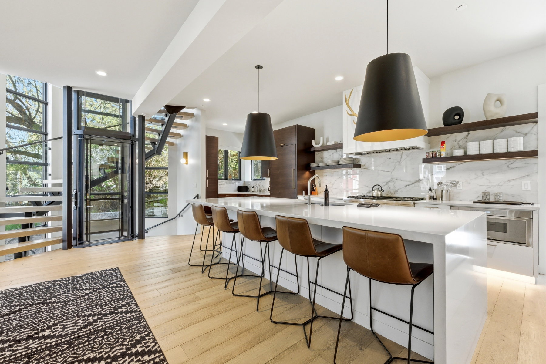 Open-concept kitchen featuring an expansive island with seating, a gas range, and a marble-patterned backsplash