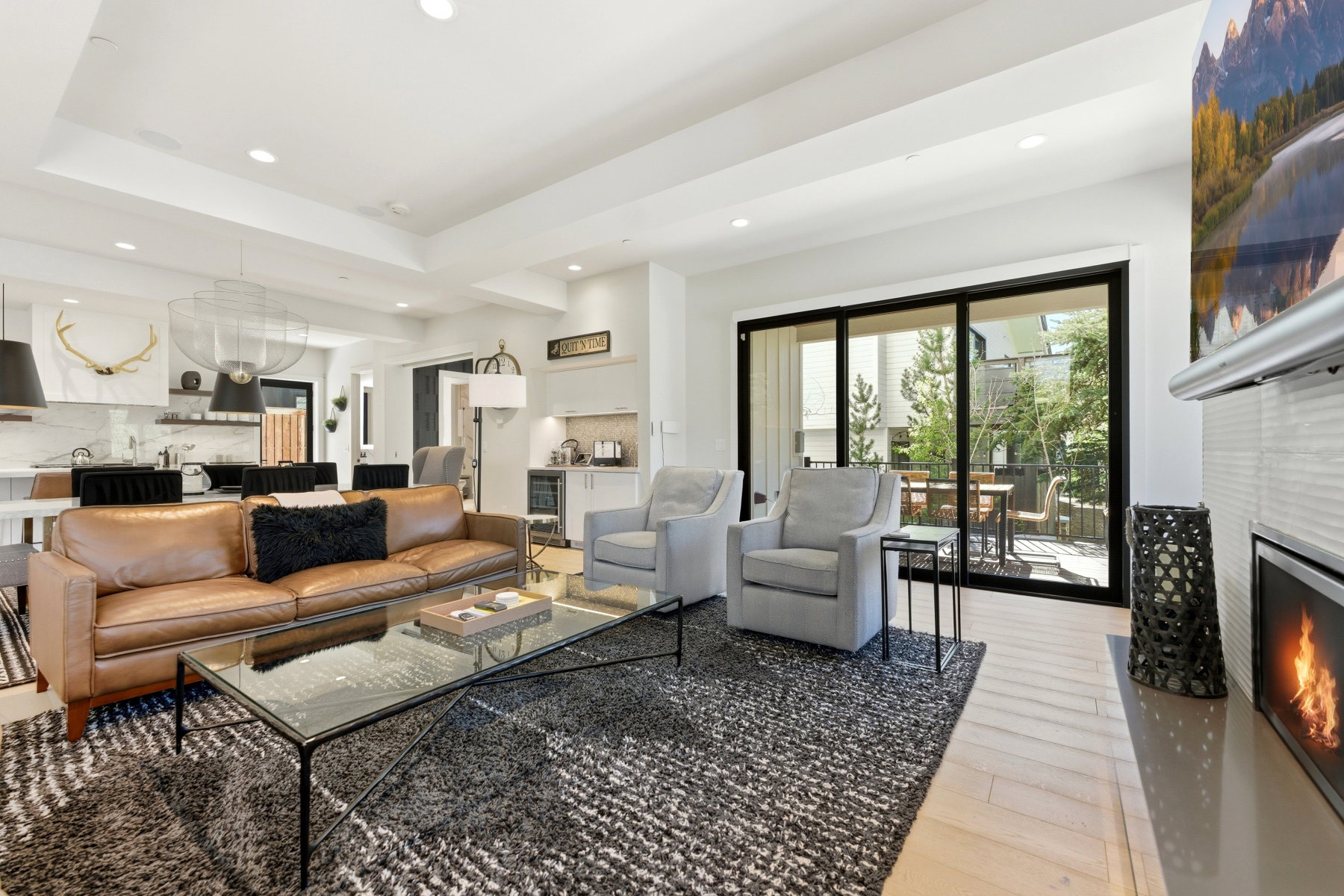 Open-concept living space featuring light wood-finish flooring, a recessed lighting scheme, and a contemporary linear fireplace