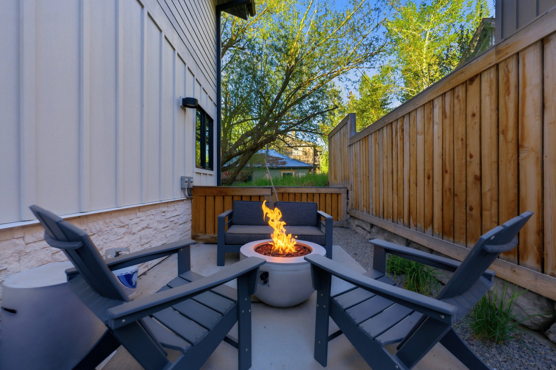 Private patio featuring a built-in fire pit, concrete flooring, stone veneer detailing, and wood fencing