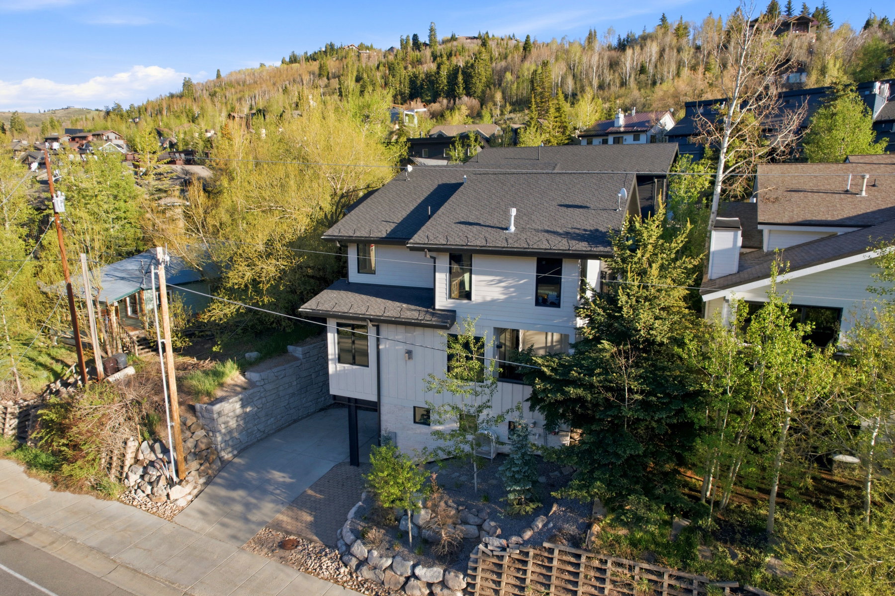 Multi-story home featuring a gray shingle roof, light-toned siding, and dark-framed windows