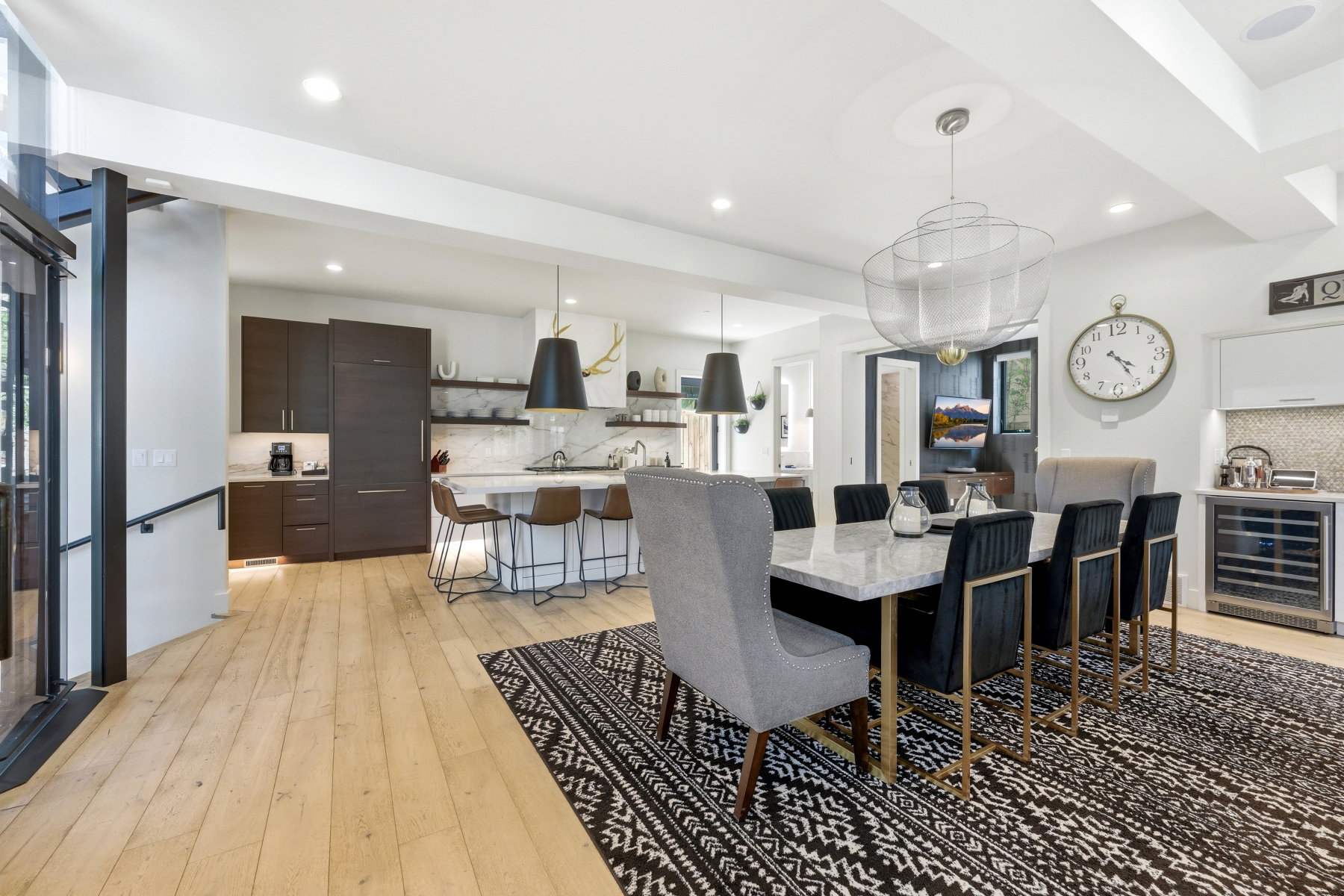 Open-concept dining area featuring light wood-finish flooring, a contemporary chandelier, recessed lighting, and a built-in wine refrigerator