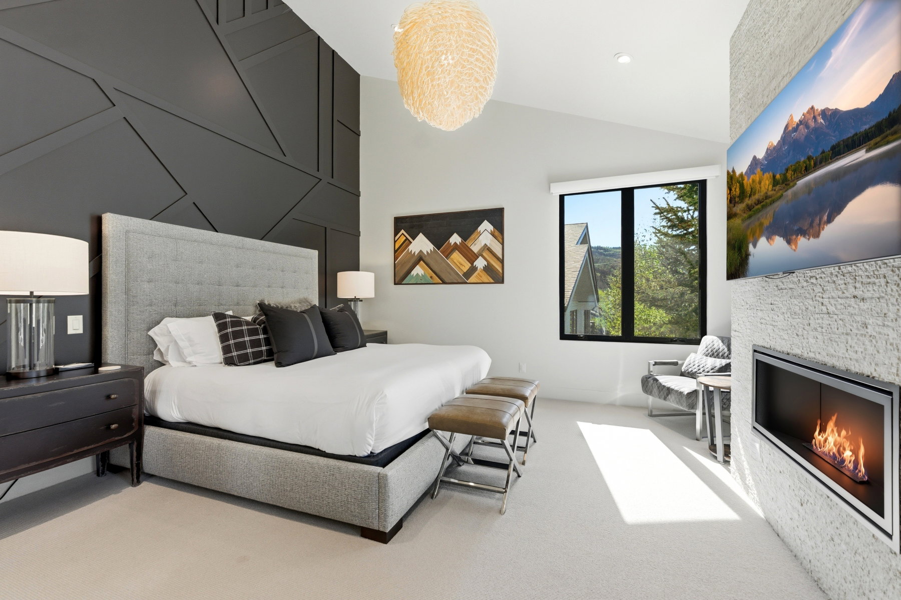 Vaulted ceilings with a statement chandelier illuminate a geometric accent wall