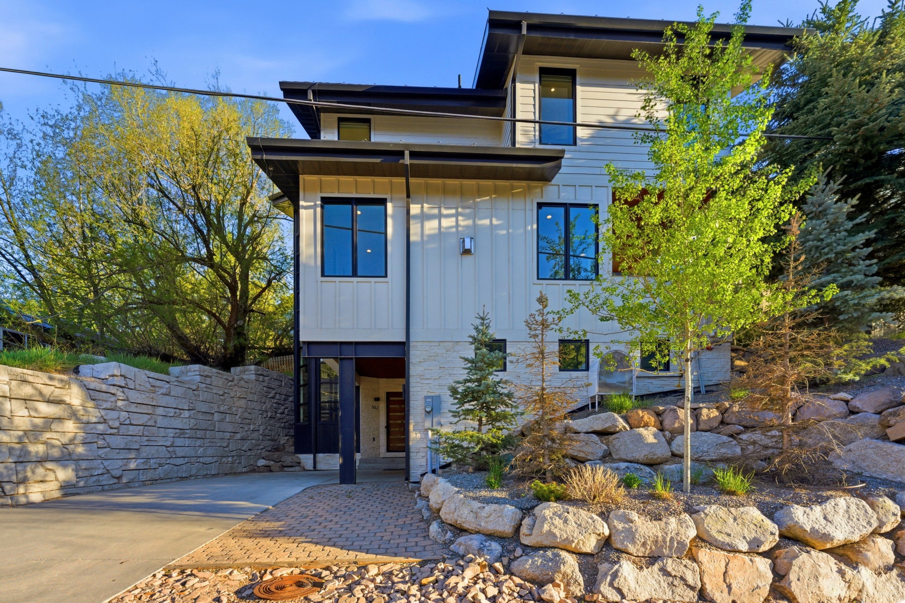 Contemporary multi-level residence featuring light-toned vertical siding and dark-trimmed windows