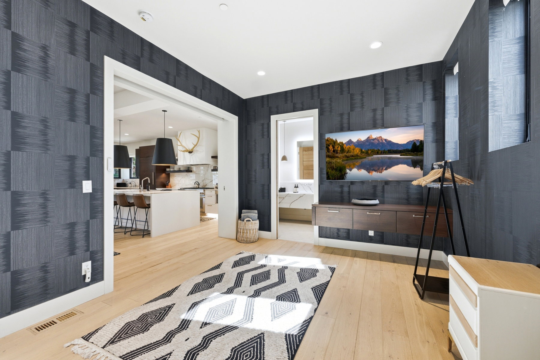 Spacious interior room featuring light wood-finish flooring and patterned wall covering