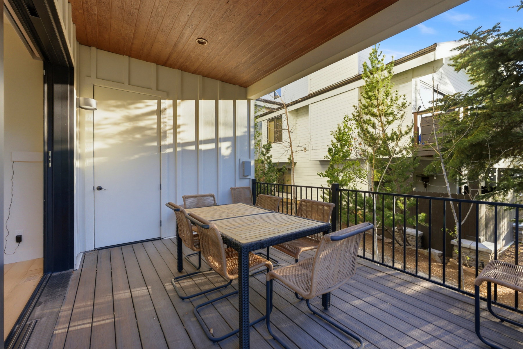 Covered outdoor deck with wood-finish ceiling, composite decking, and black metal railings