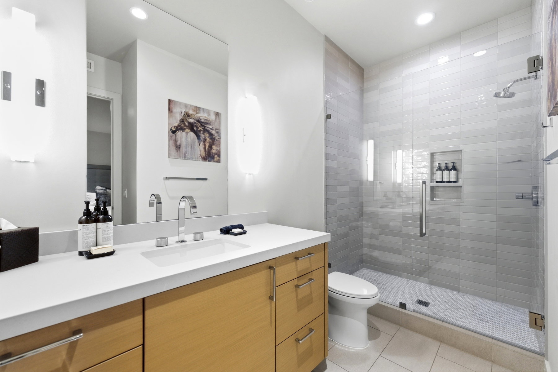 Modern bathroom featuring a spacious glass-enclosed shower with tiled walls and a recessed niche