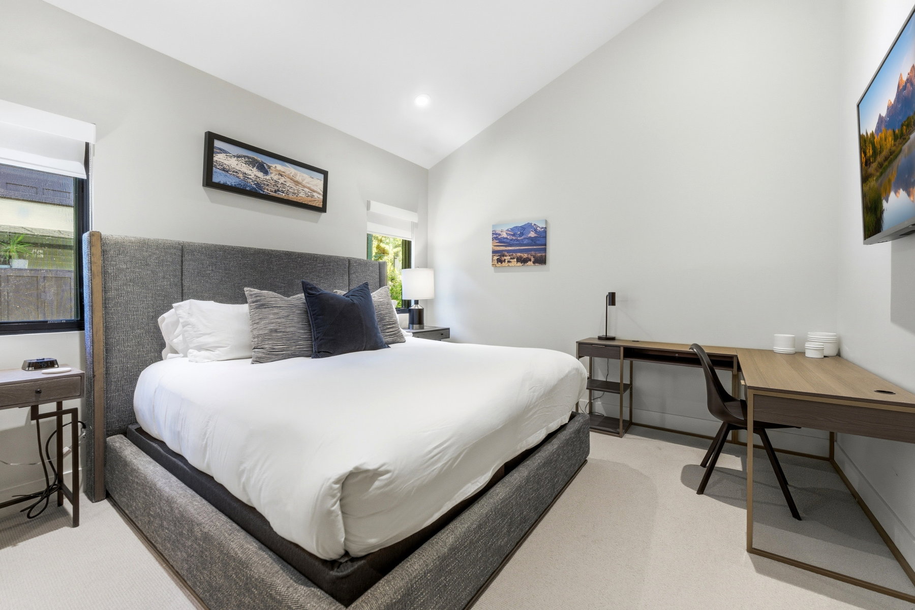 Vaulted ceilings highlight this spacious room, featuring recessed lighting, large windows with roller shades, and light-colored flooring