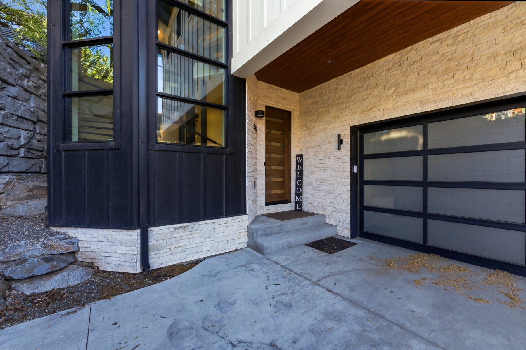 Contemporary exterior with multi-pane windows, a modern wood-panel entry door, and a frosted glass garage door