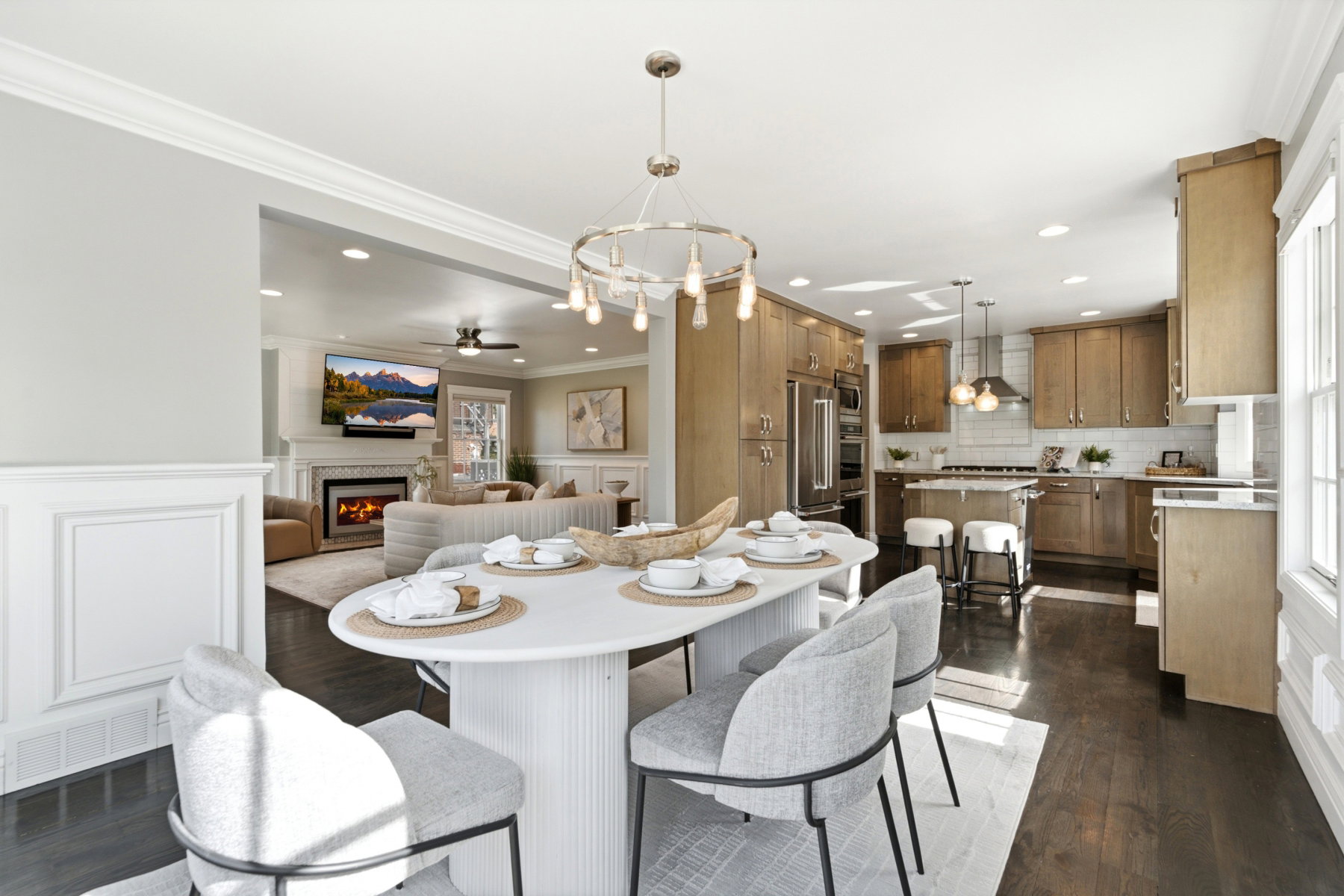 Open-concept dining area with dark wood-finish flooring, a contemporary chandelier, and wainscoting