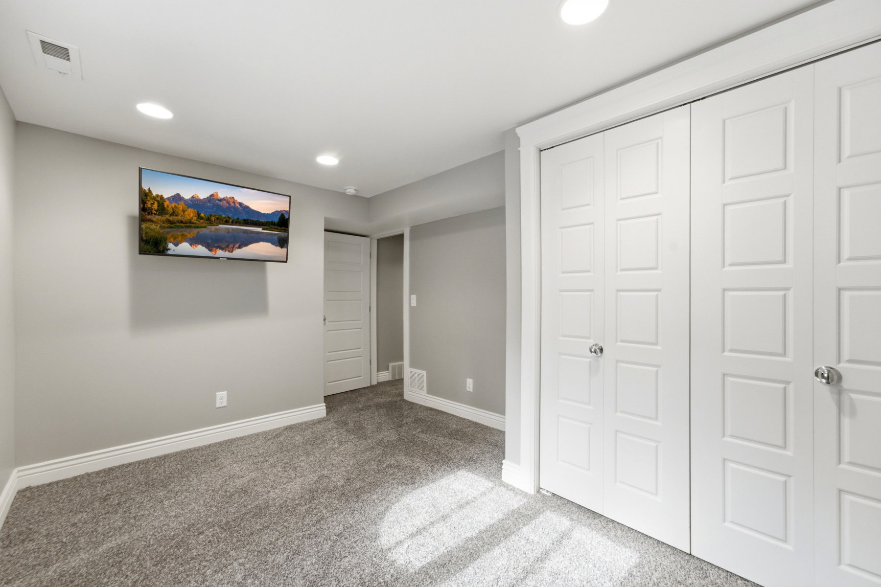 Room featuring light gray walls, gray carpet flooring, and white baseboards