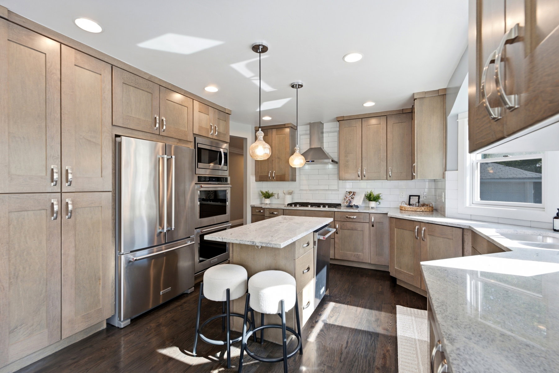 Kitchen featuring light wood-finish cabinetry, stainless steel appliances, a center island with pendant lighting, and light-toned countertops