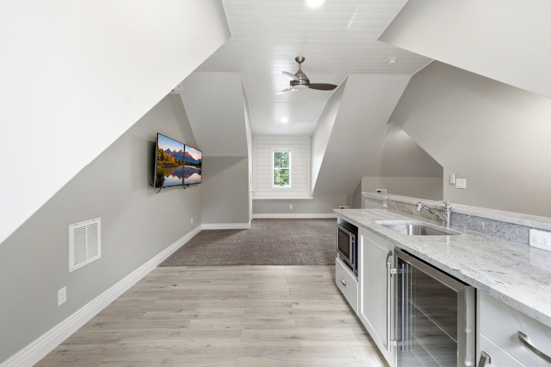 Attic living space featuring a wet bar with a stainless steel sink, under-counter beverage cooler, and microwave