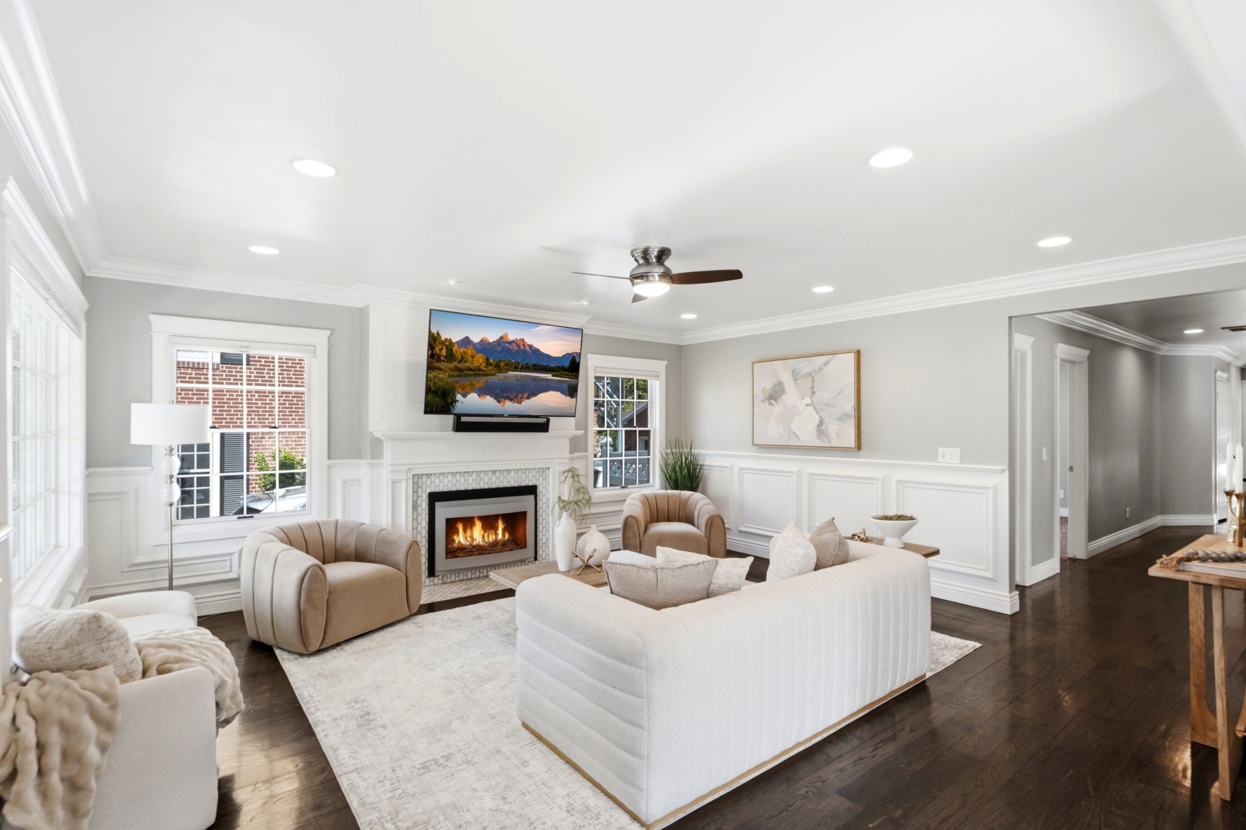 Living space with dark wood-finish flooring, white wainscoting, and crown molding
