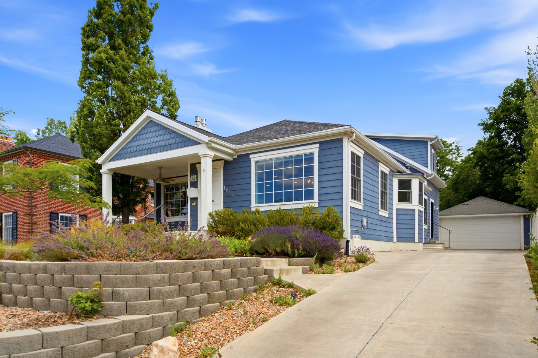 Blue siding exterior with white trim, featuring a covered front porch with columns and a gable roof