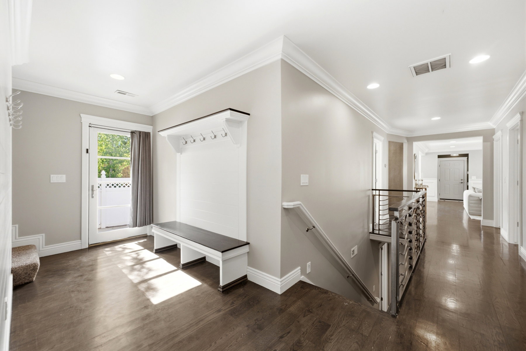 Entryway featuring built-in bench seating with coat hooks, wood-finish flooring, recessed lighting, and crown molding