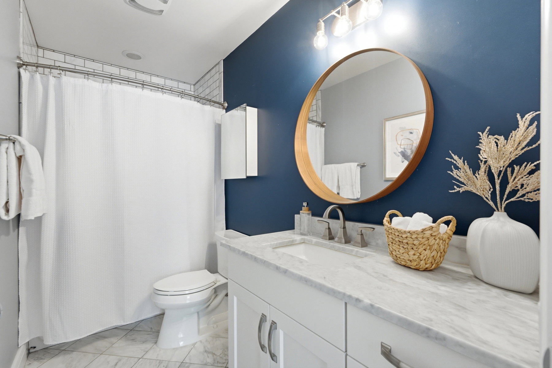 Bathroom featuring a white vanity with marble countertop, undermount sink, and brushed nickel faucet