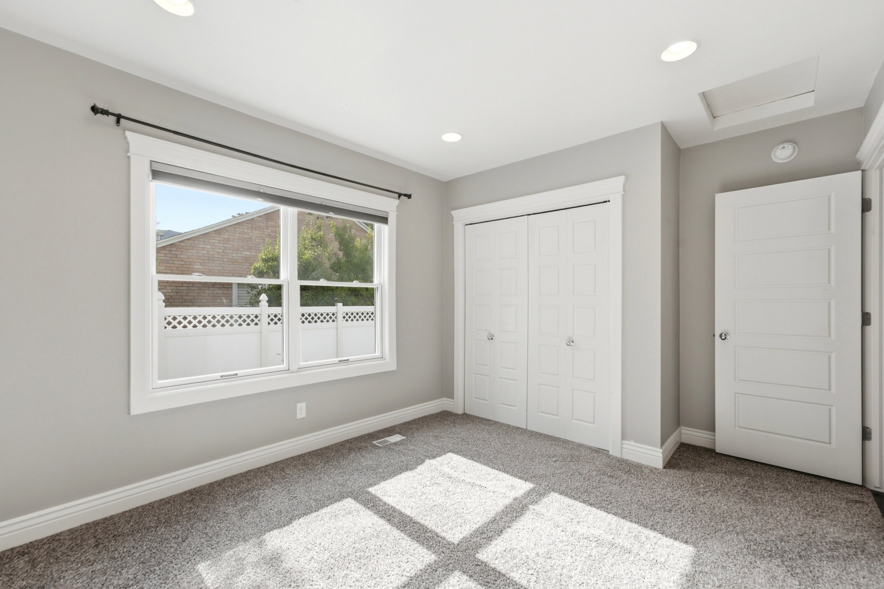 Room featuring light gray wall paint, gray textured carpeting, white trim, recessed lighting, and a double-pane window with a black curtain rod
