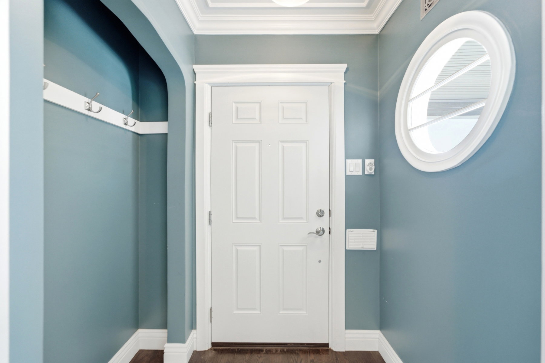 Entryway featuring a paneled door, decorative crown molding, and wood-finish flooring