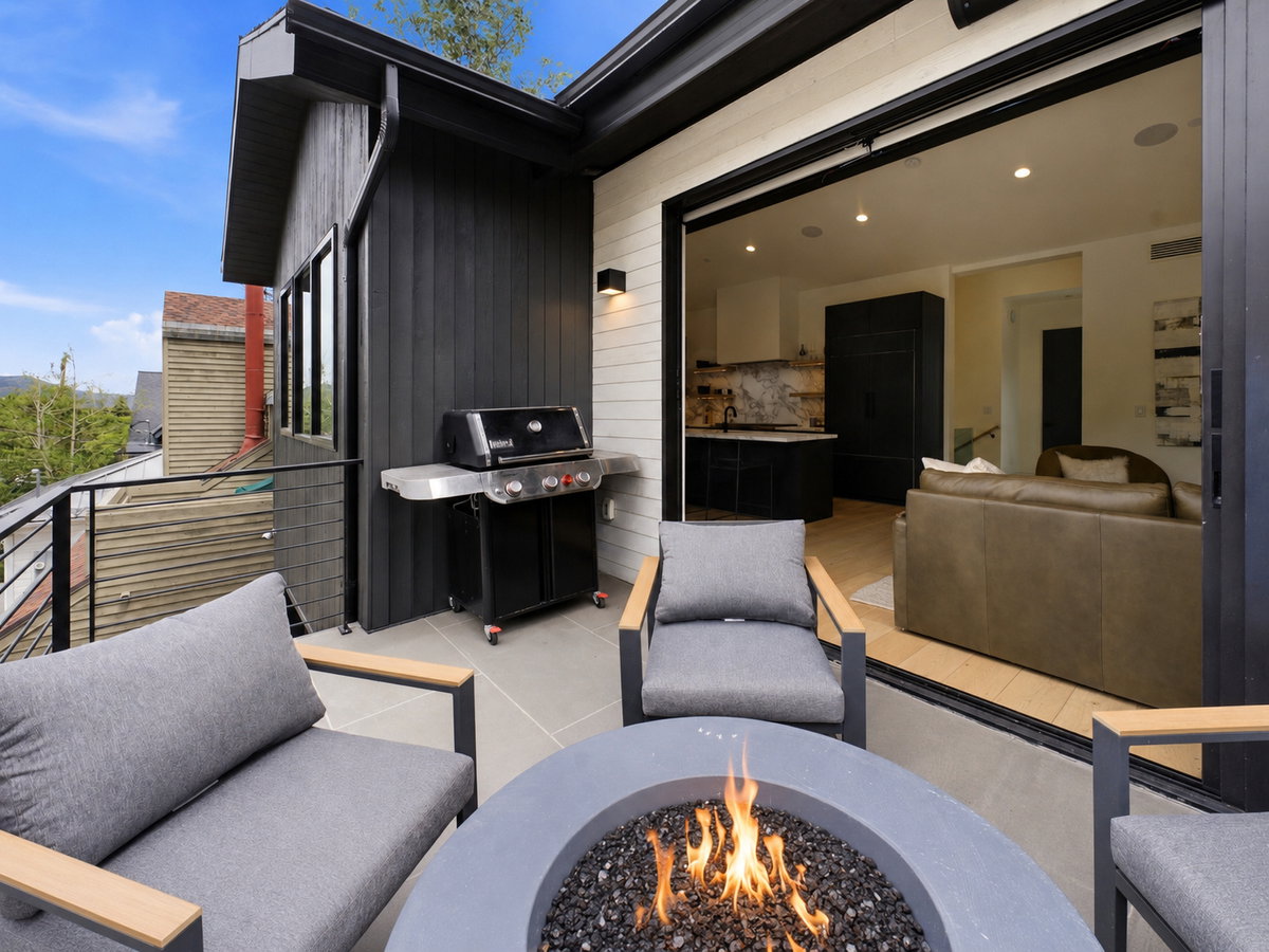 Outdoor patio featuring a built-in fire pit, sleek railing, and direct access to interior living spaces via a wide sliding door