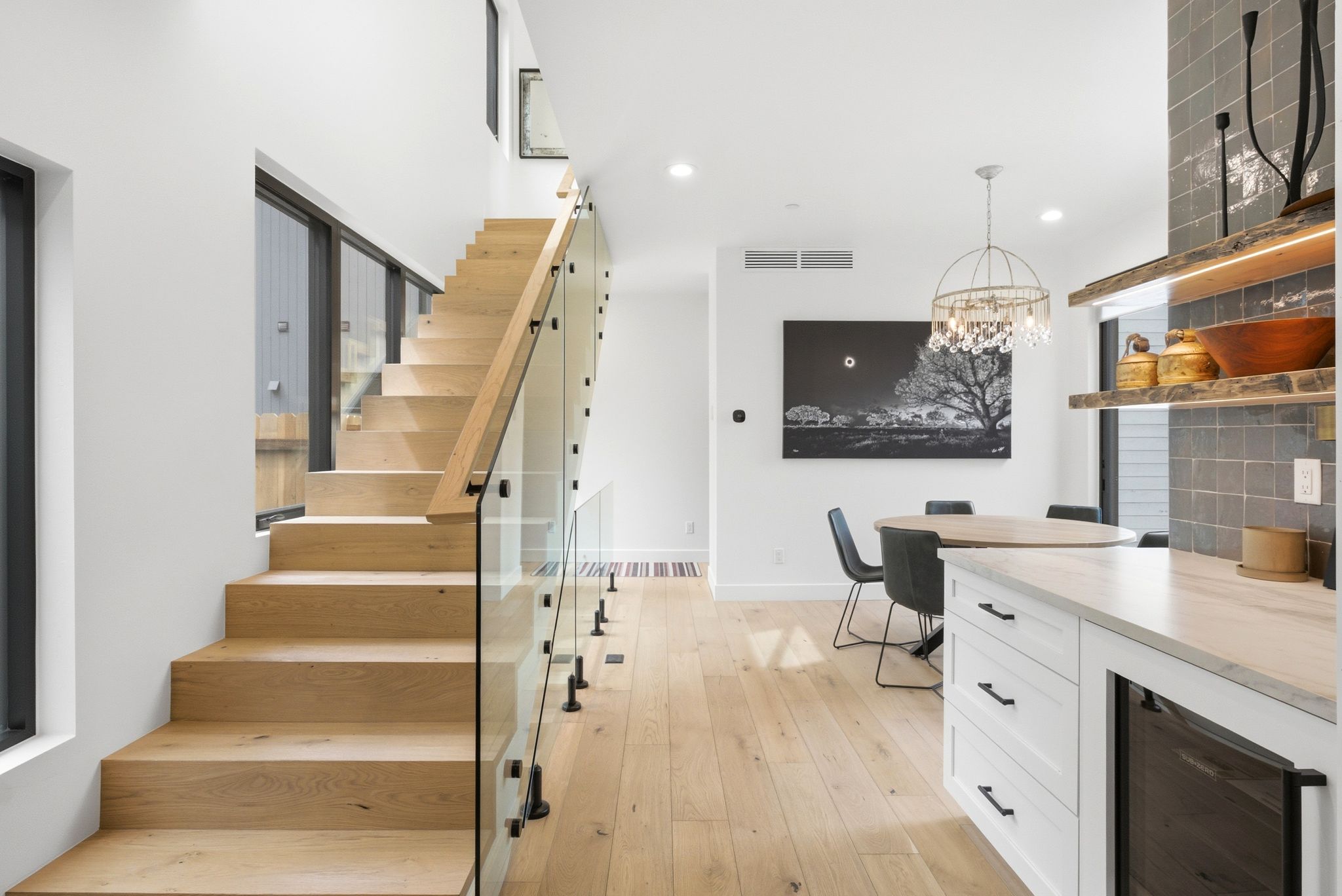 Modern staircase featuring wood-finish treads and a clear glass railing system with matte black hardware