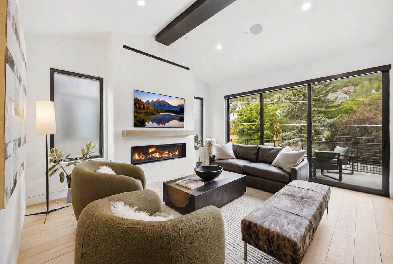 Spacious living area featuring a modern linear fireplace with a light wood mantel, extensive sliding glass doors, a frosted privacy window, recessed ceiling lighting, and light wood-finish flooring