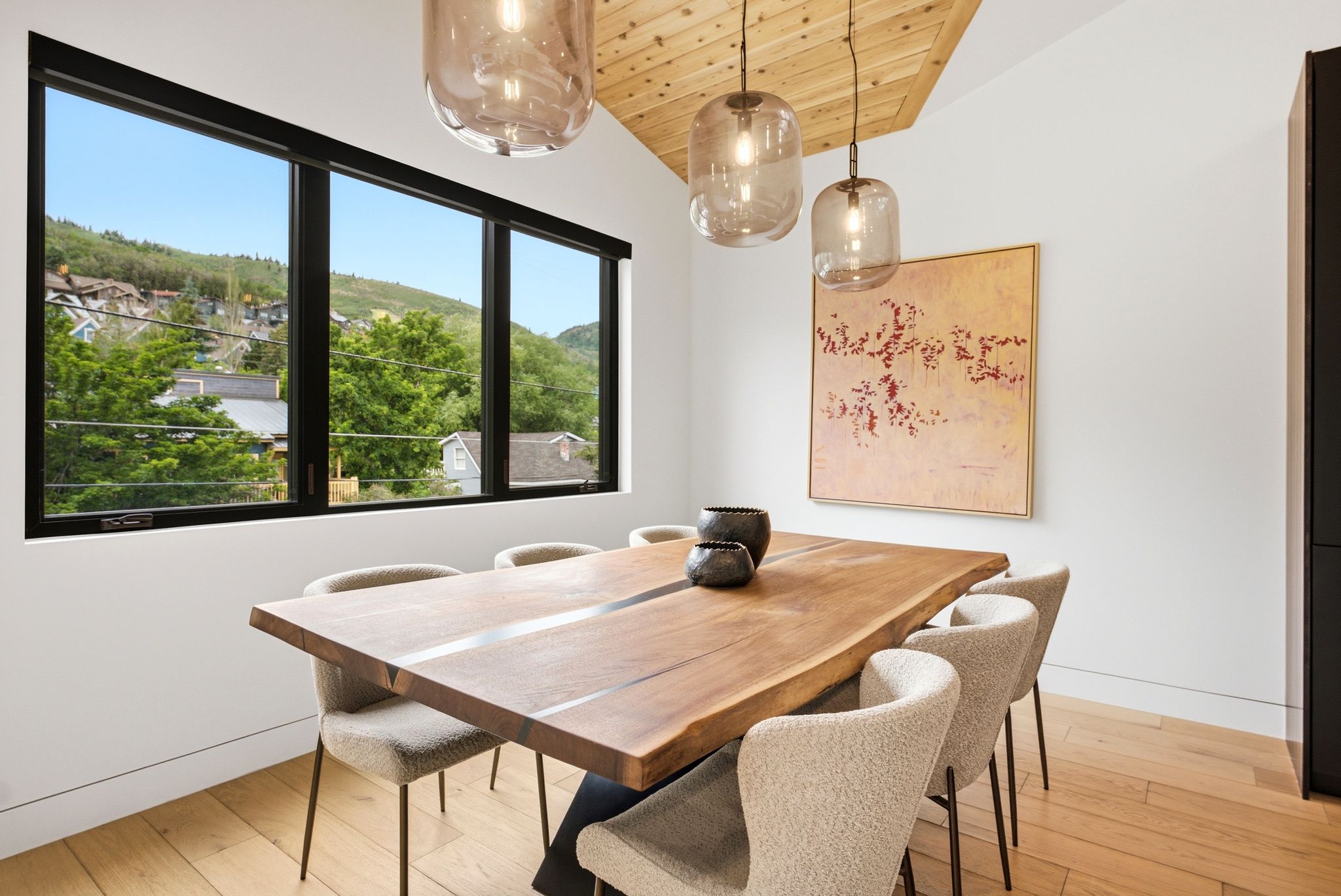 Dining area featuring a vaulted wood-paneled ceiling, large black-framed windows, and hardwood flooring