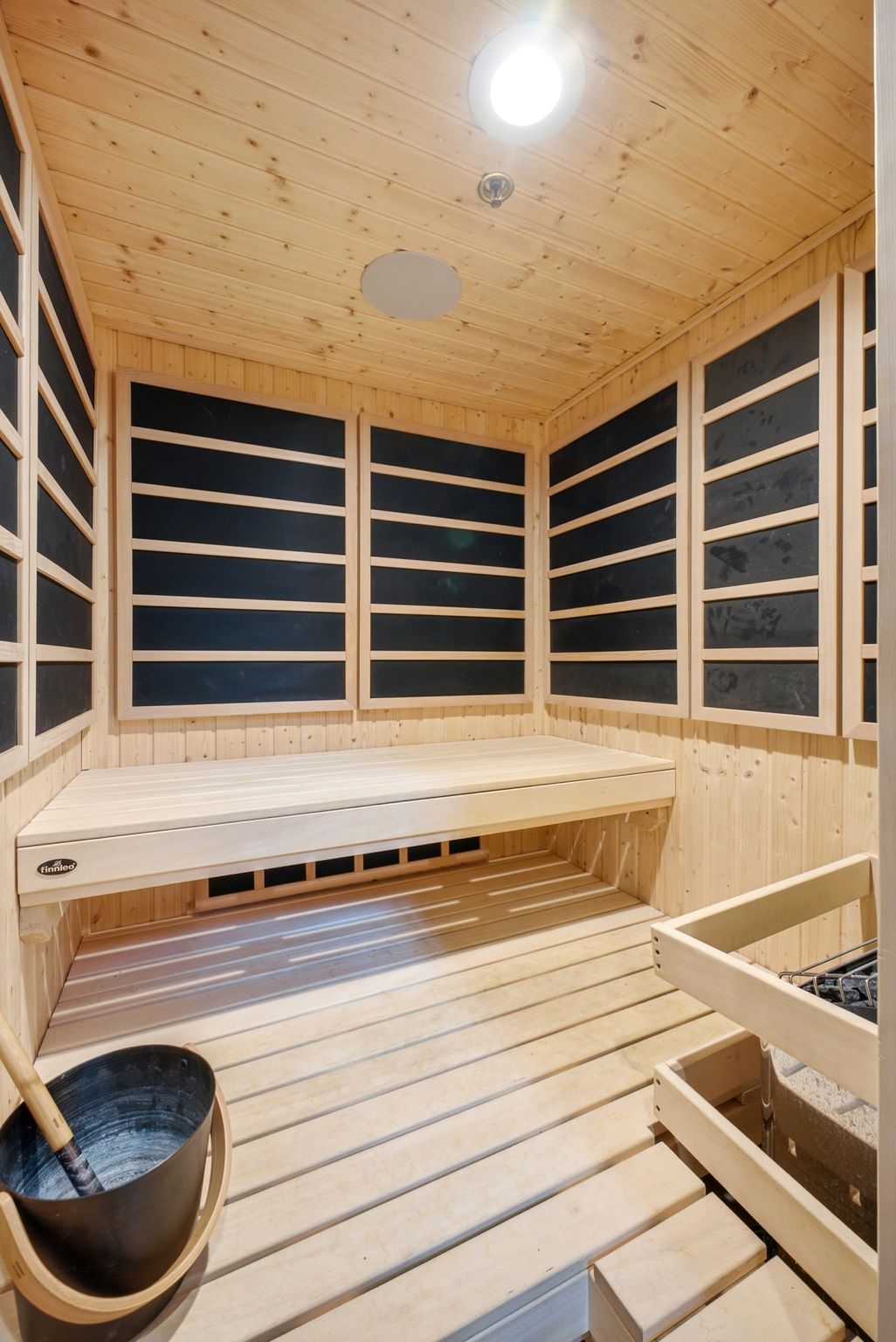 Wood-paneled sauna featuring a built-in bench, slatted flooring, and integrated wall heating elements