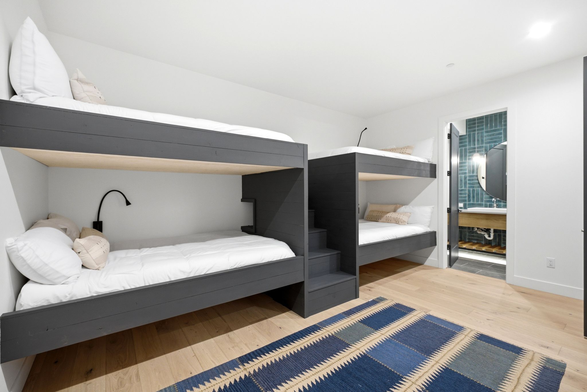 Built-in bunk beds with integrated steps, individual reading lights, and wood-finish flooring