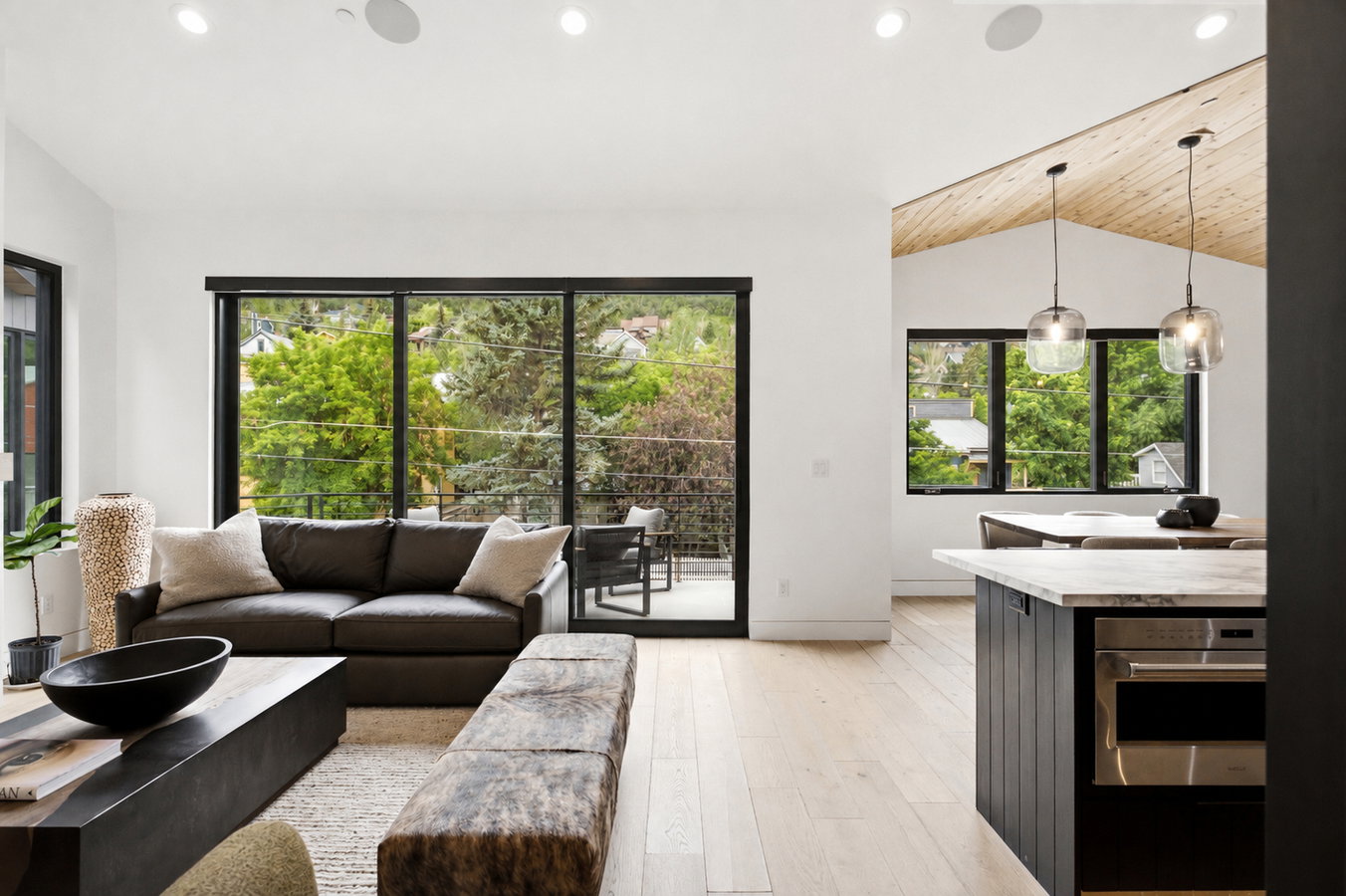 Open-concept living area featuring a vaulted wood-finish ceiling, light wood-finish flooring, recessed lighting, and a large sliding glass door