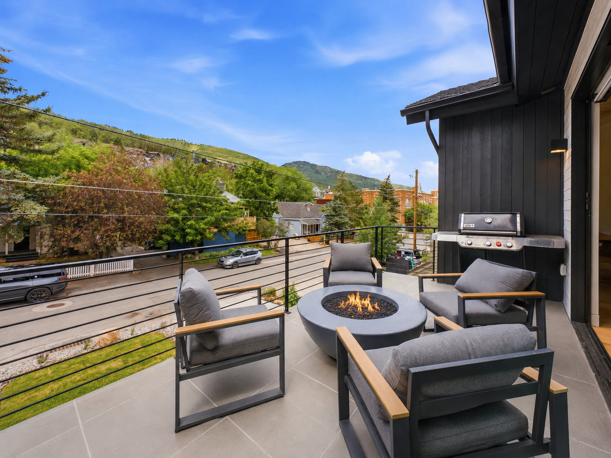 Spacious outdoor patio featuring stone-finish tile flooring, a built-in gas grill, and a modern fire pit