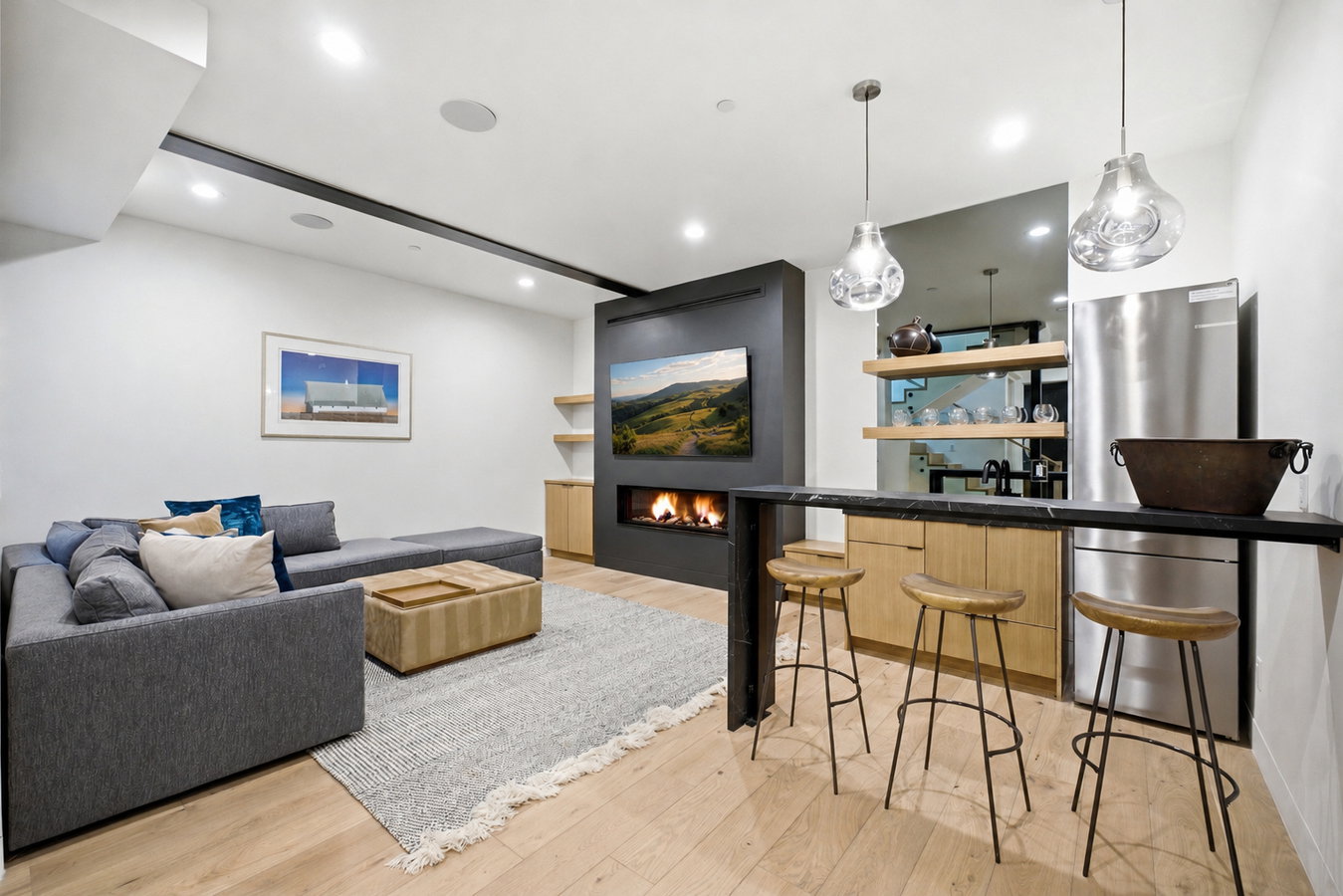 Entertainment area featuring a linear fireplace, built-in media console, light wood-finish flooring, and recessed lighting