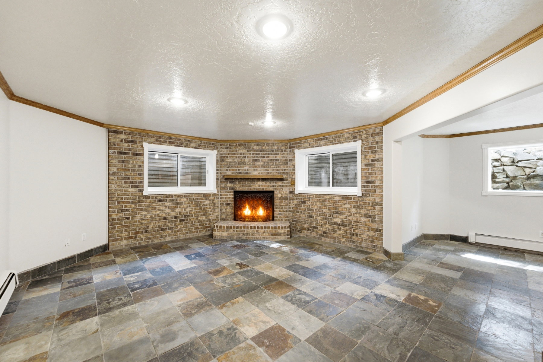 Spacious room featuring a brick fireplace, multi-toned slate tile flooring, and recessed lighting