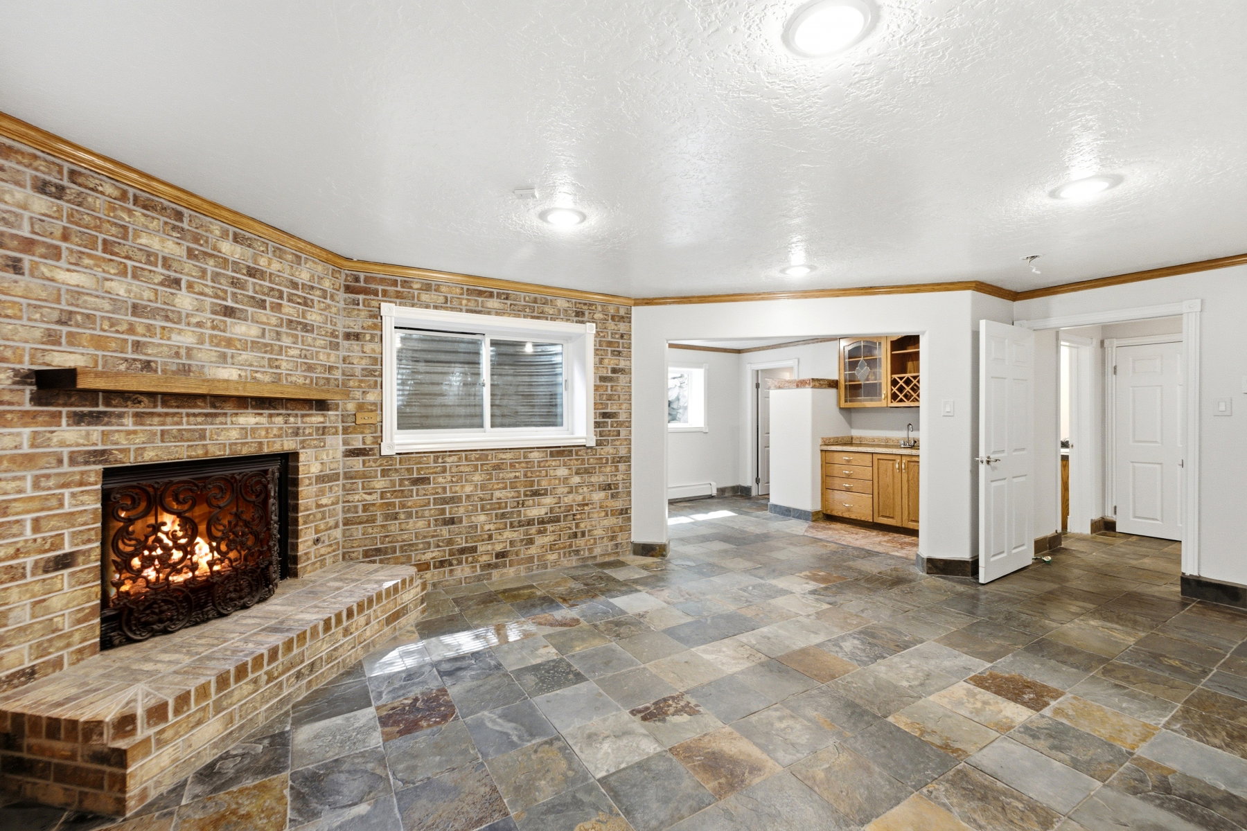 Brick accent wall featuring a wood-mantle fireplace