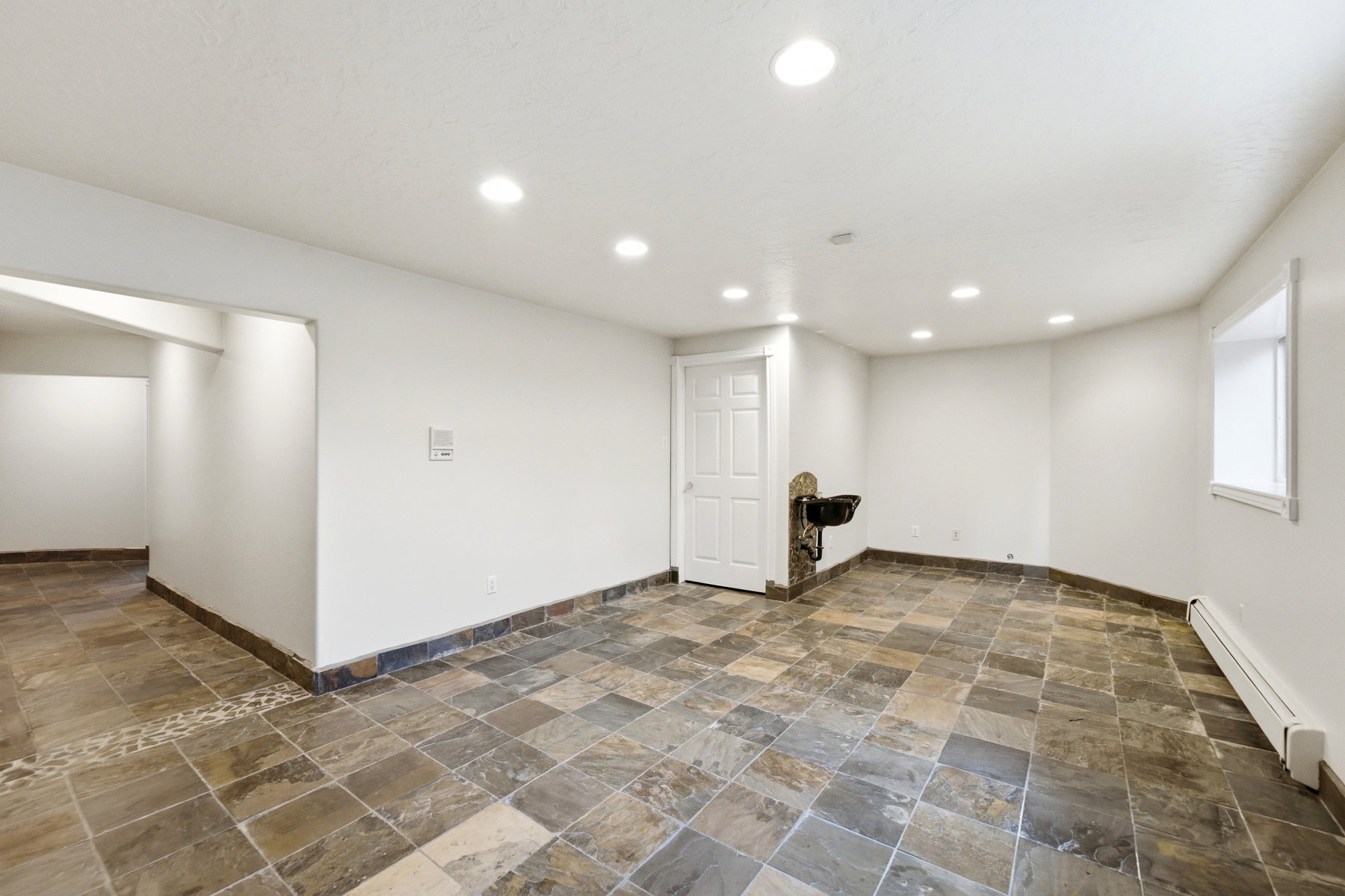 Spacious room featuring mixed-tone slate tile flooring, white walls, and recessed lighting