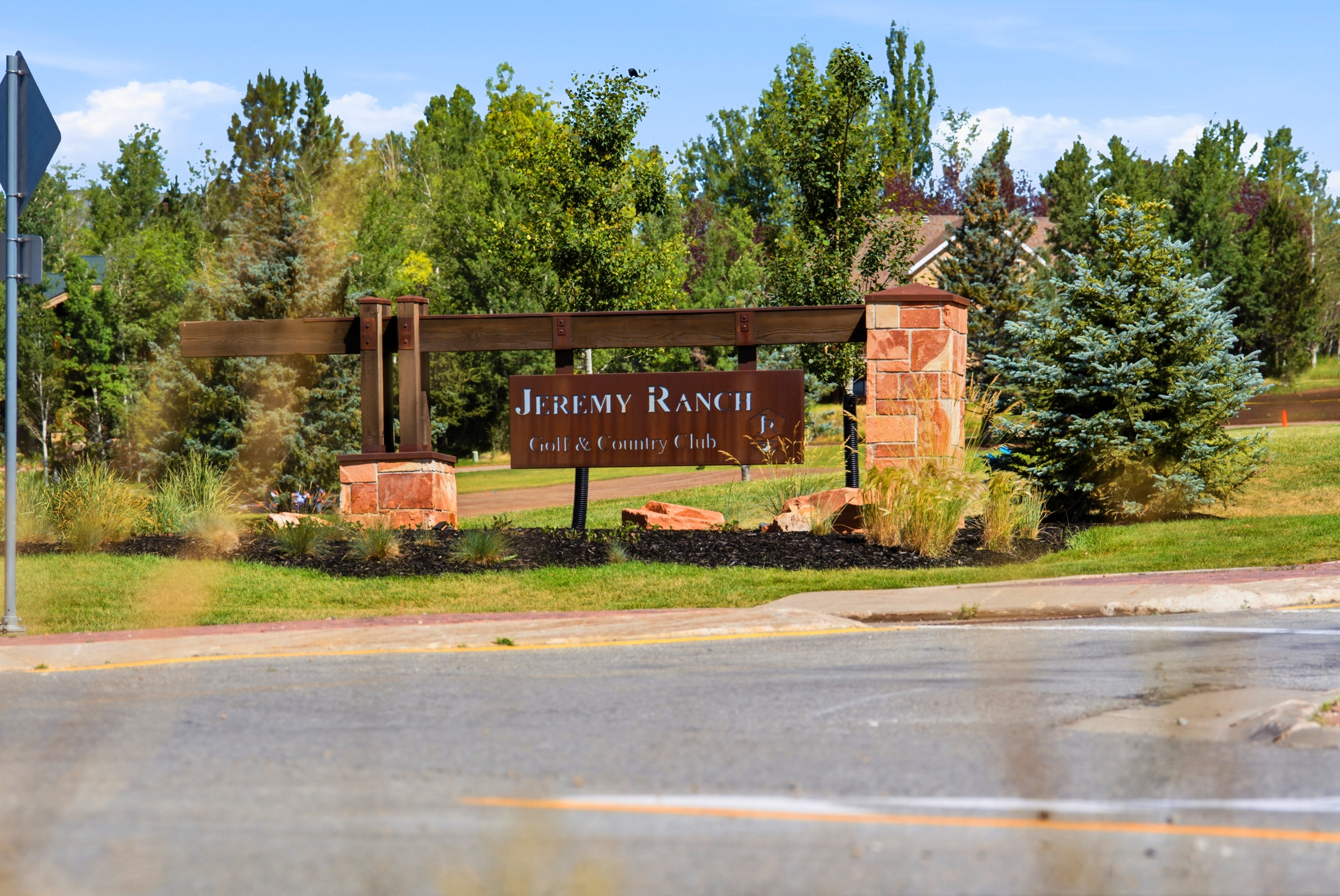 Community entrance sign featuring stone pillars and a dark metal archway