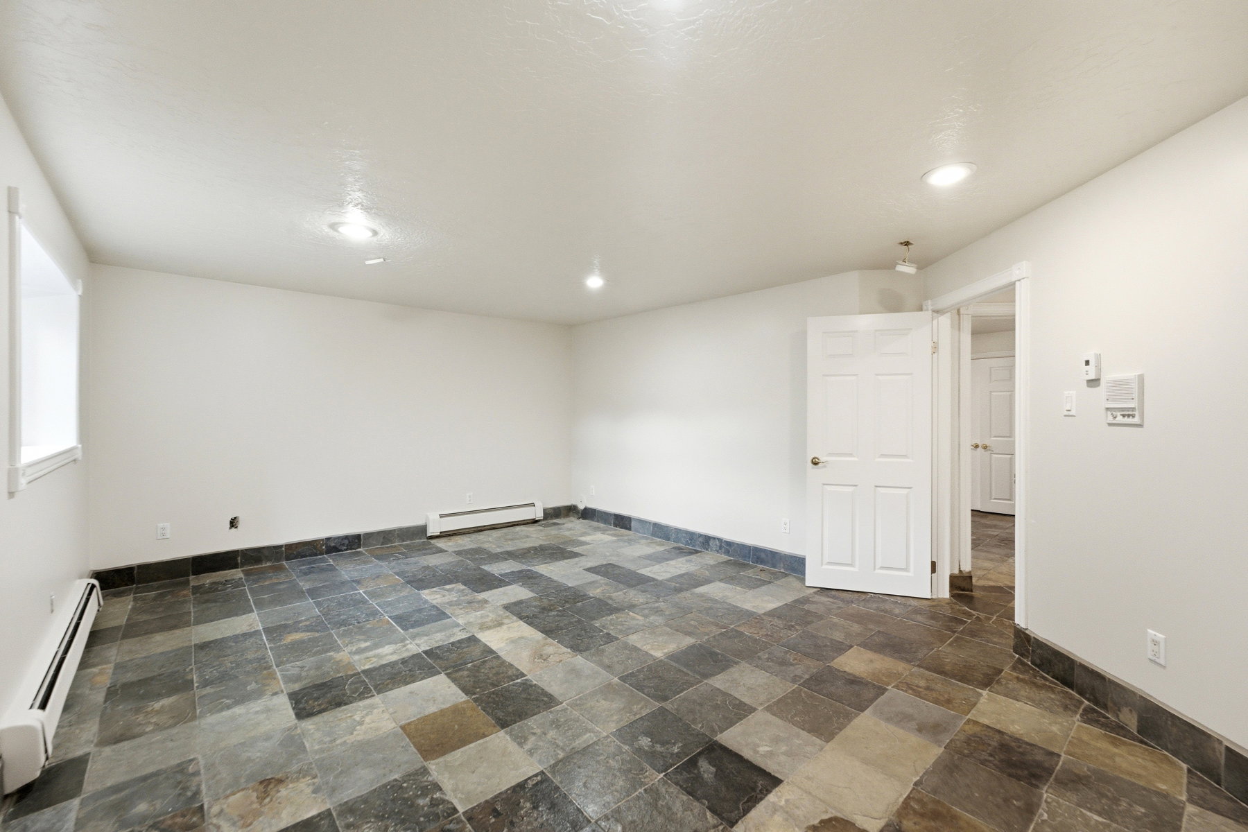 Spacious room featuring multi-tone slate tile flooring, white painted walls, and recessed ceiling lighting