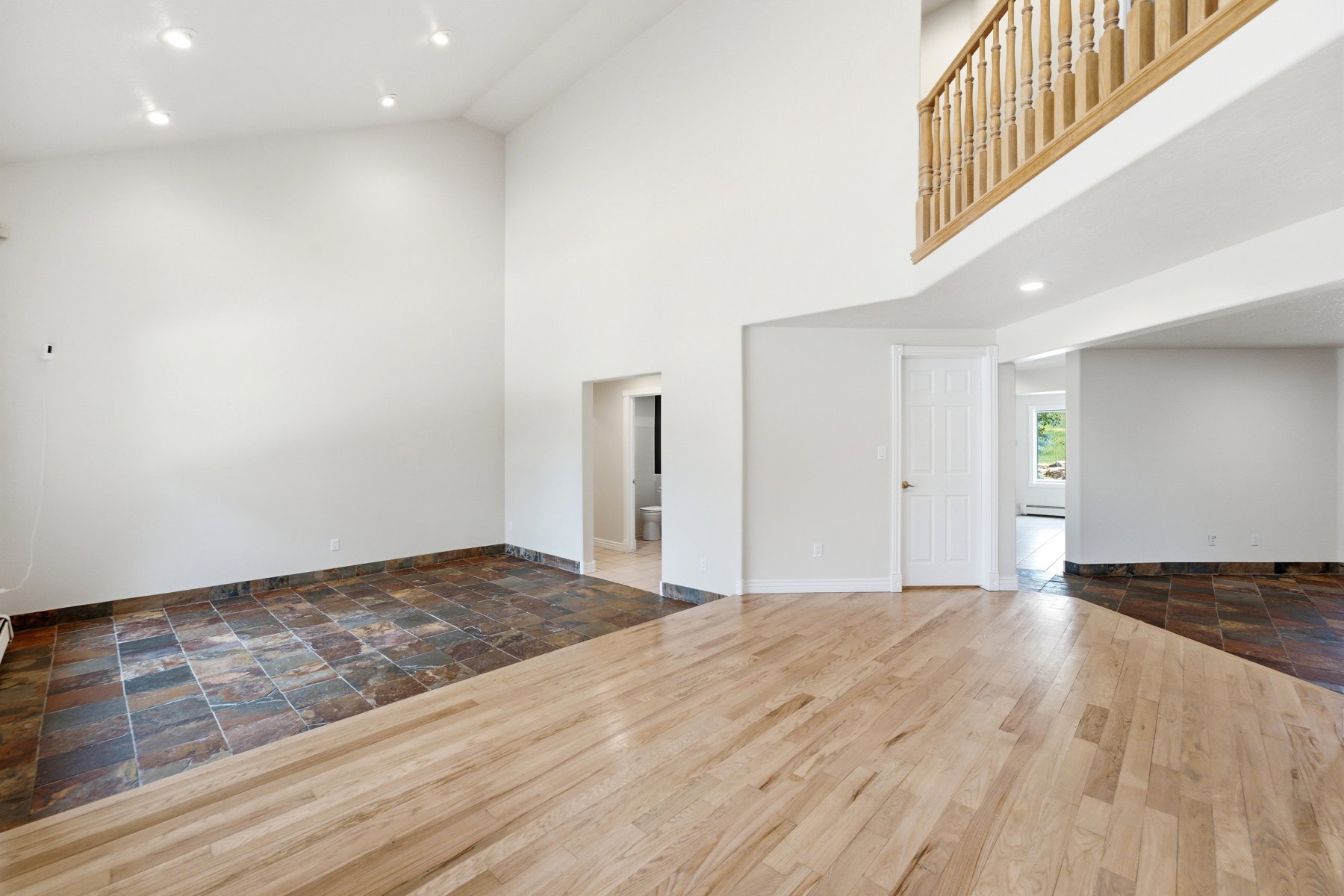 Spacious interior featuring a high vaulted ceiling, recessed lighting, and a combination of wood-finish flooring and large format slate tile