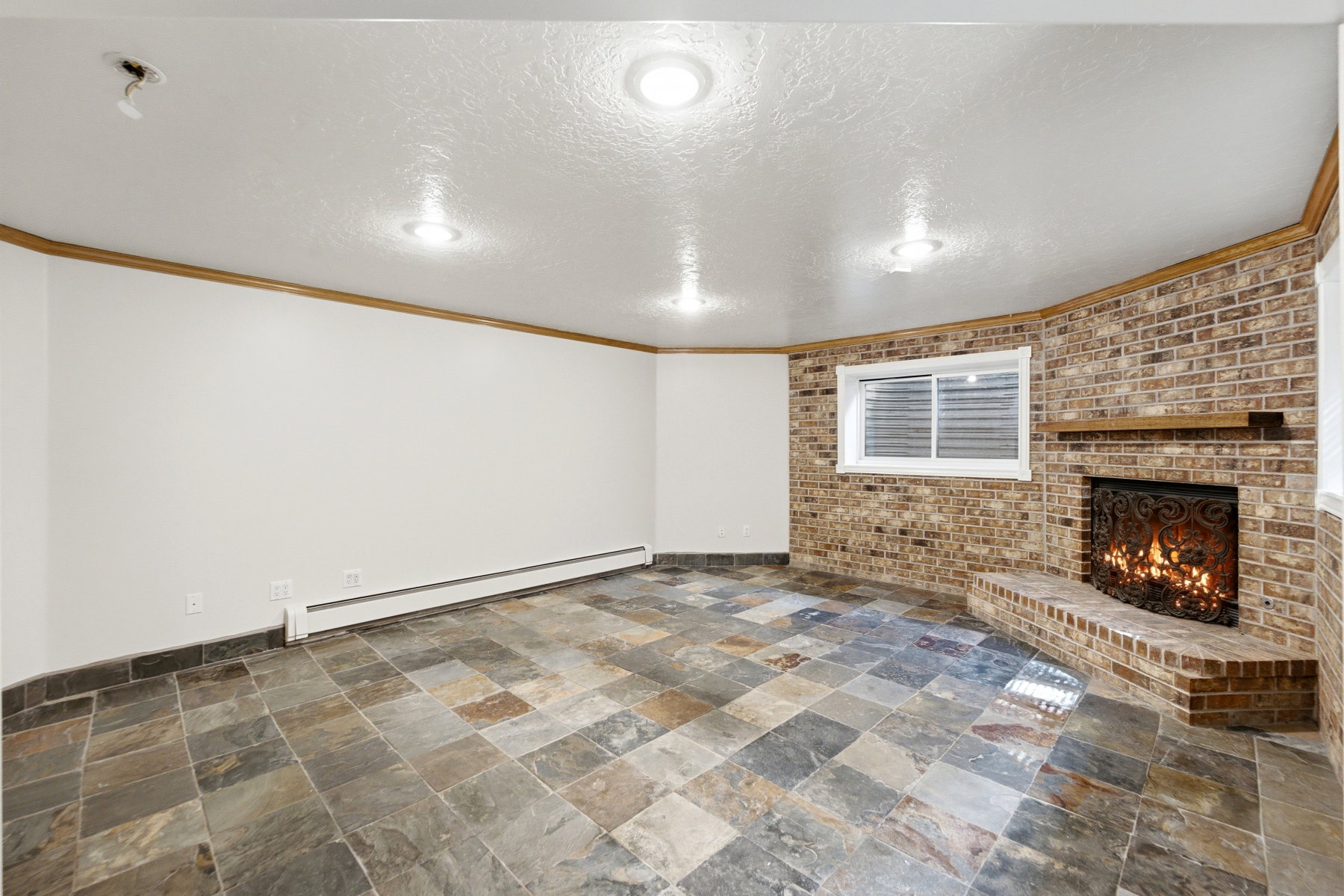Spacious room featuring a corner brick fireplace with a decorative screen