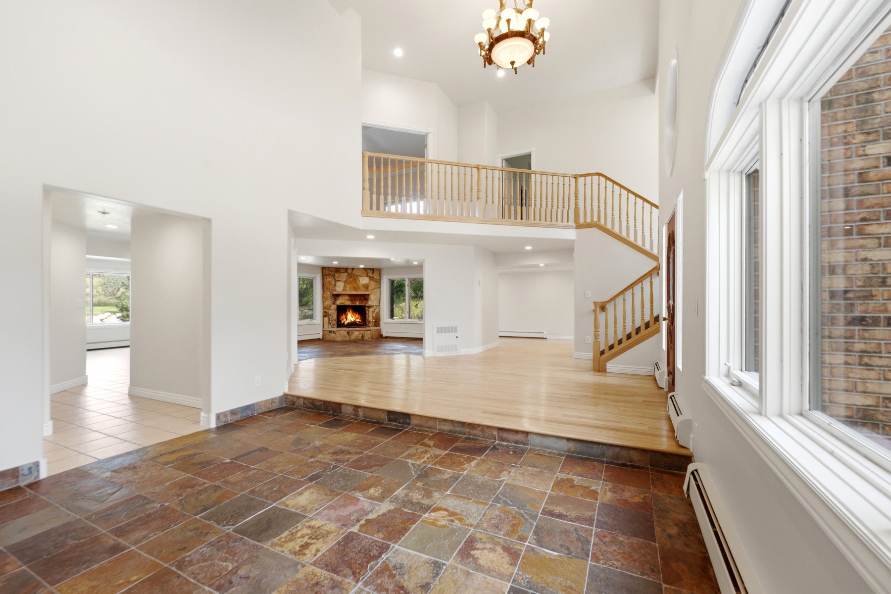 Two-story foyer featuring natural stone tile flooring, a hardwood staircase with wood railings, a multi-level layout, and an upper-level balcony
