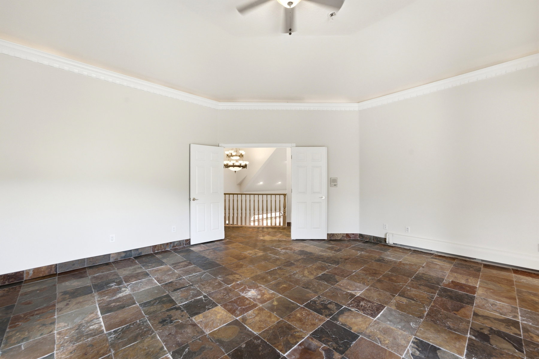 Spacious room featuring slate tile flooring, white walls, and elegant crown molding